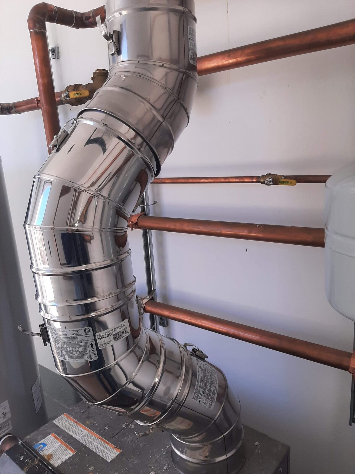 Polished metal flue system installed in a mechanical room